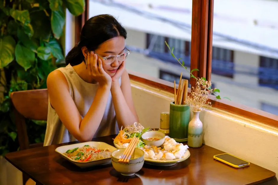 A young woman enjoys a traditional Vietnamese meal at a cozy indoor restaurant in Da Nang.