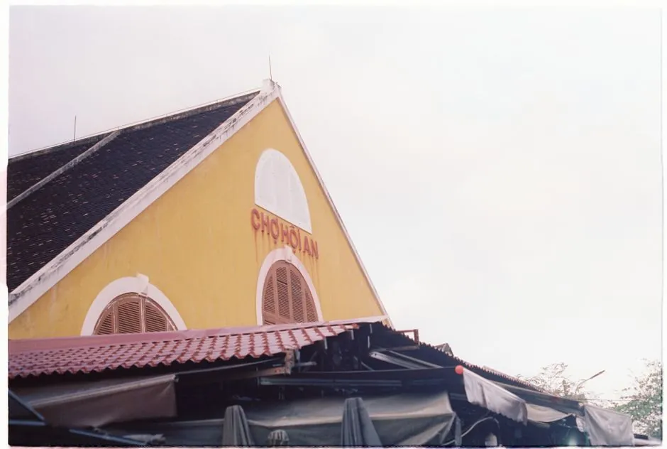View of the Chợ Hội An market building's yellow facade in daylight.