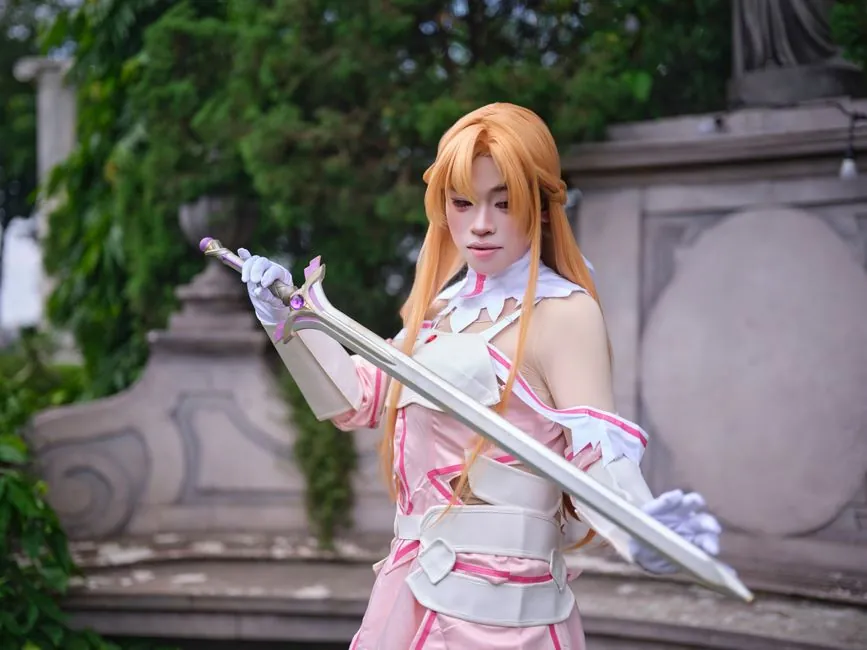 A cosplayer in a detailed Sword Art Online costume, posing with confidence outdoors.